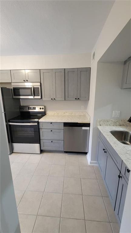 kitchen featuring sink, light tile patterned floors, gray cabinetry, and stainless steel appliances