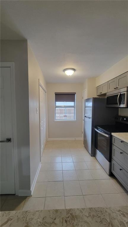 kitchen with light tile patterned floors, appliances with stainless steel finishes, and gray cabinets