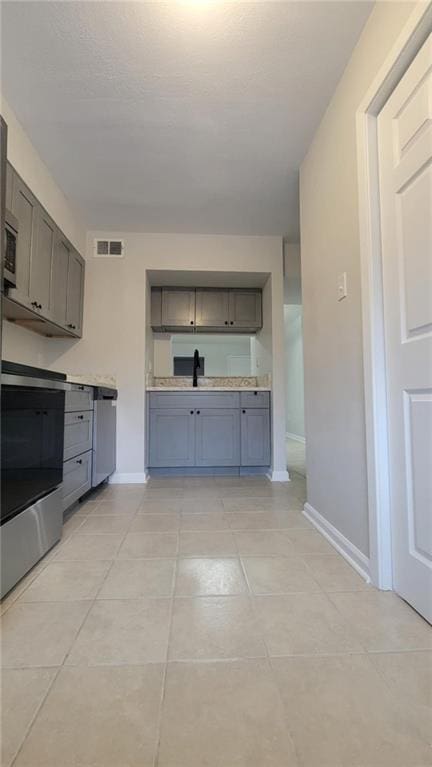 kitchen featuring sink, gray cabinetry, light tile patterned floors, and stainless steel electric range