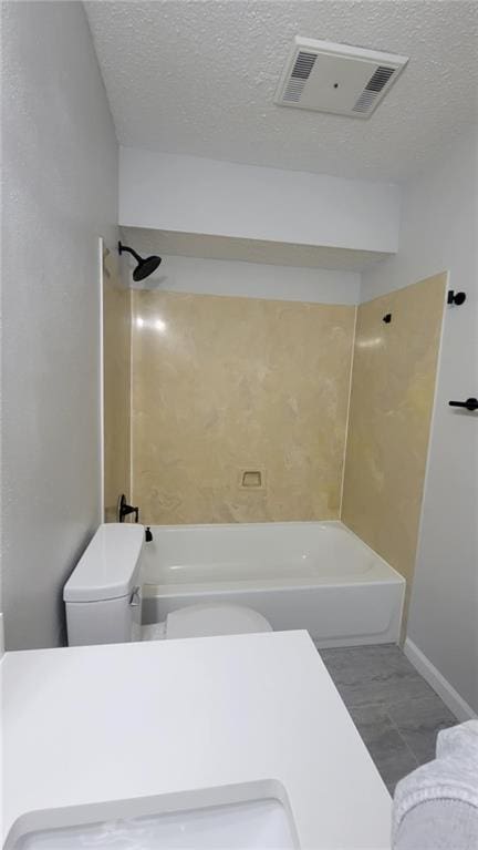 bathroom with tub / shower combination, a textured ceiling, toilet, and tile patterned flooring