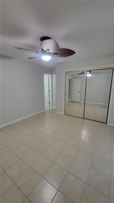 empty room with ceiling fan and light tile patterned floors