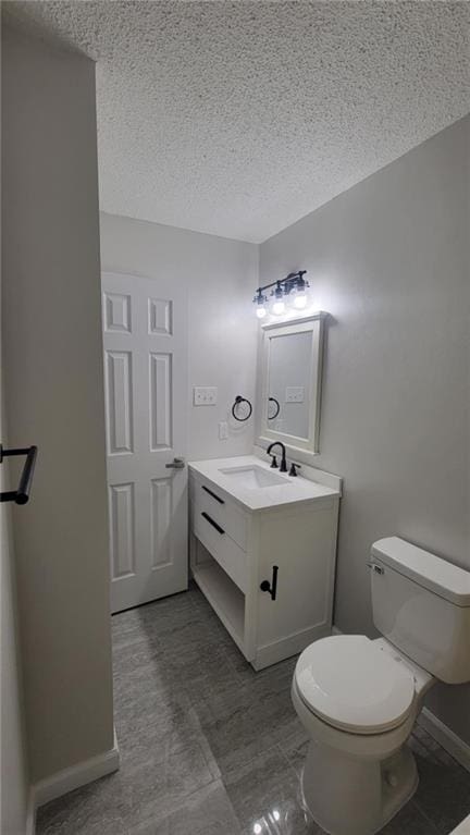 bathroom with a textured ceiling, toilet, and vanity