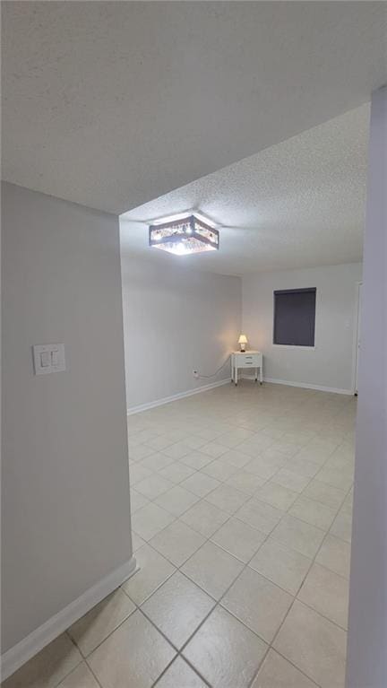 spare room featuring light tile patterned floors and a textured ceiling