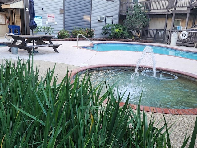 view of swimming pool with a wall unit AC and pool water feature