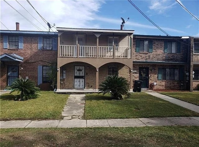 view of front facade featuring a balcony and a front yard