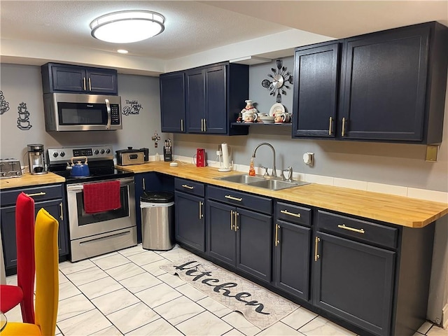 kitchen featuring sink, light tile patterned floors, stainless steel appliances, and wood counters