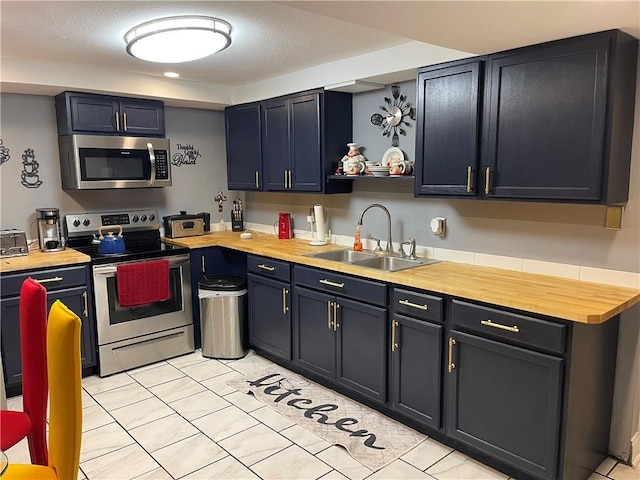 kitchen featuring butcher block countertops, appliances with stainless steel finishes, sink, and light tile patterned floors