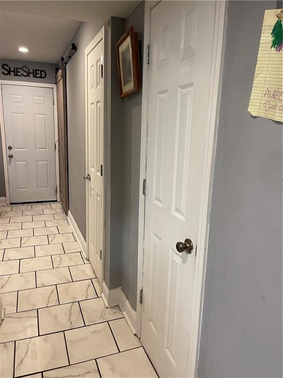 hallway featuring light tile patterned floors and a barn door