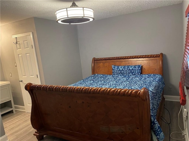 bedroom featuring a textured ceiling and light hardwood / wood-style flooring