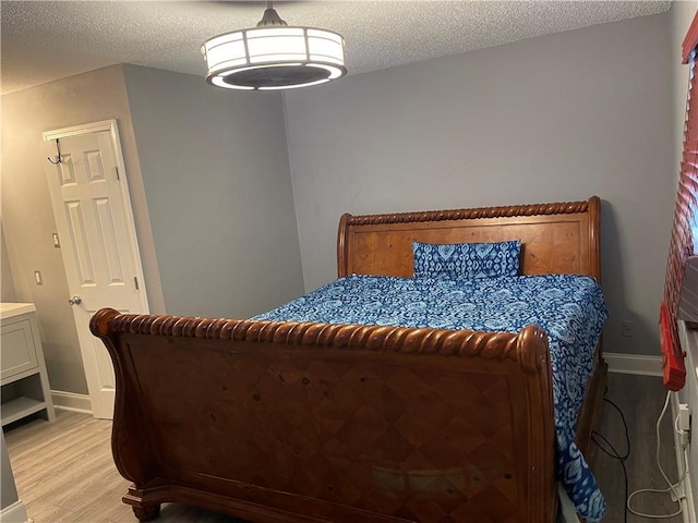 bedroom with a textured ceiling and light hardwood / wood-style flooring