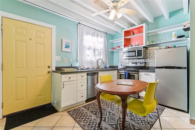 2301 Dauphine St, New Orleans, LA 70117 - kitchen featuring white cabinetry, light tile patterned floors, beam ceiling, and appliances with stainless steel finishes