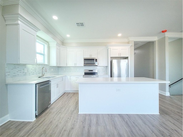 kitchen with appliances with stainless steel finishes, backsplash, a kitchen island, white cabinets, and sink