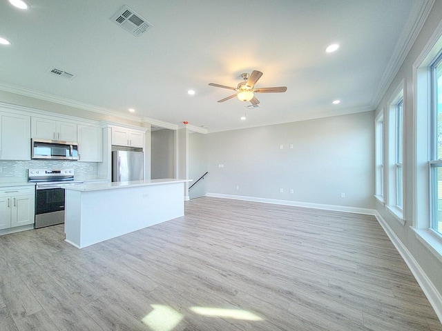 kitchen featuring white cabinets, backsplash, appliances with stainless steel finishes, and a kitchen island