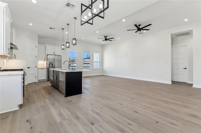 kitchen with decorative light fixtures, an island with sink, white cabinetry, and stainless steel appliances