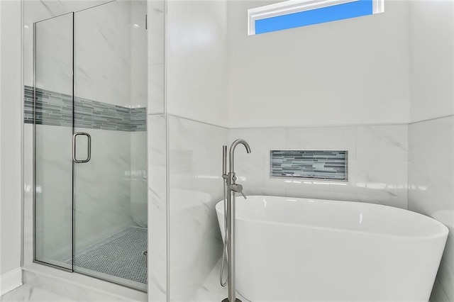 bathroom featuring shower with separate bathtub and tile walls