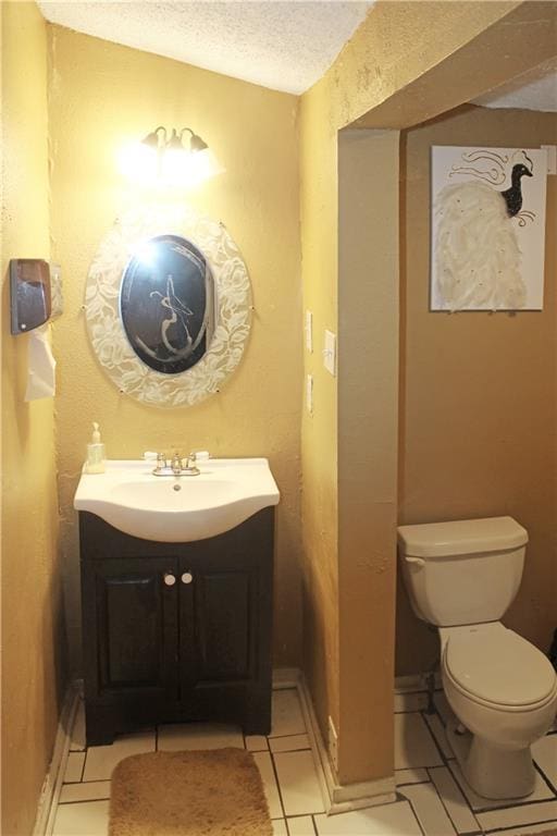 bathroom with a textured ceiling, tile patterned floors, vanity, and toilet