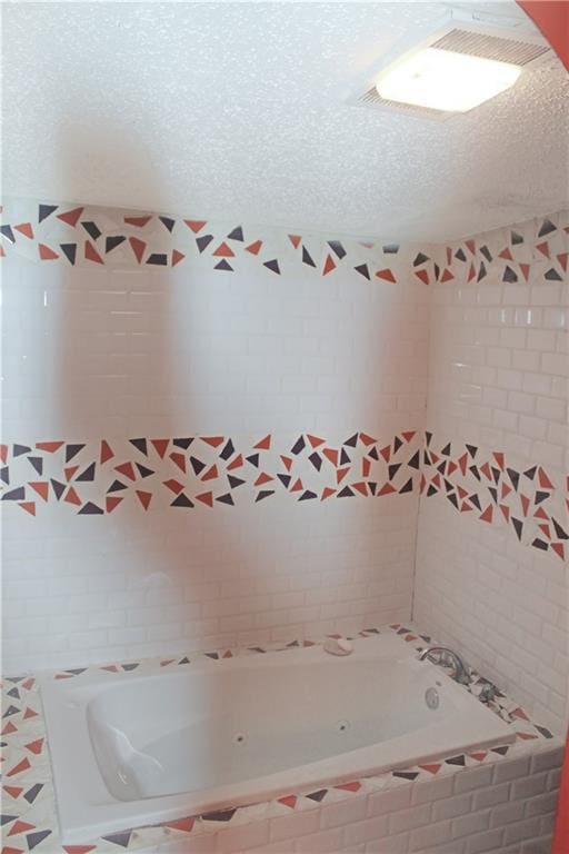 bathroom featuring a relaxing tiled tub and a textured ceiling