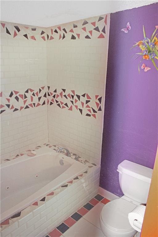 bathroom with toilet, tile patterned flooring, and tiled tub