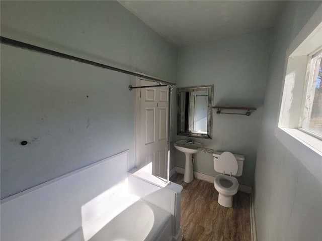 bathroom with a tub to relax in, sink, toilet, and hardwood / wood-style flooring