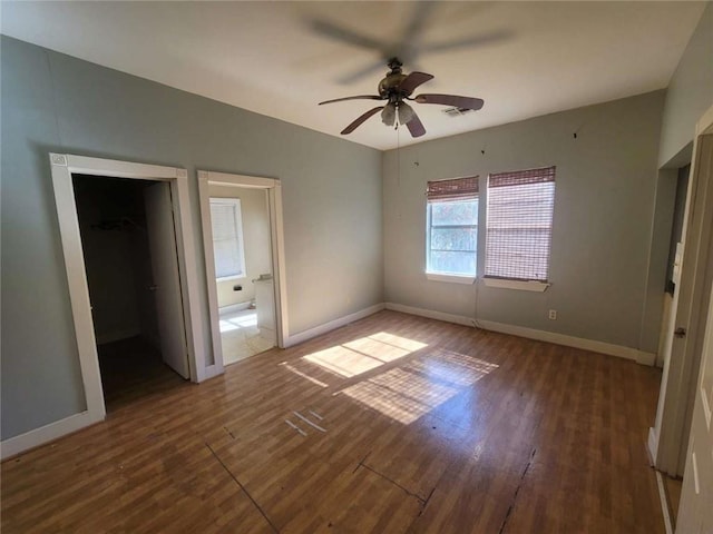 unfurnished bedroom with a spacious closet, ceiling fan, dark hardwood / wood-style flooring, and a closet