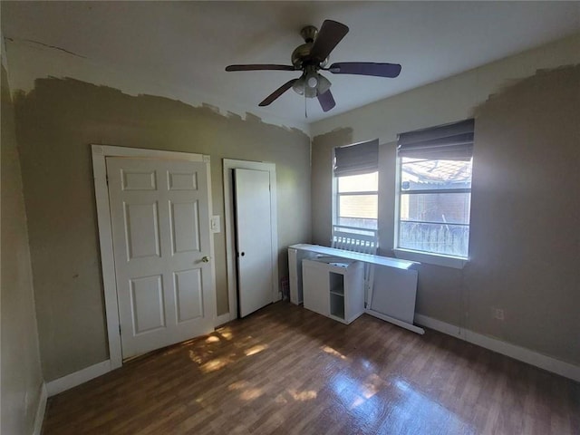 unfurnished bedroom featuring ceiling fan and dark hardwood / wood-style flooring