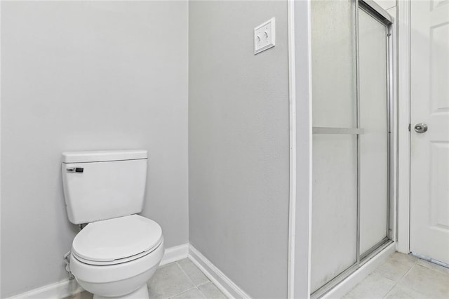 bathroom featuring tile patterned floors, toilet, and a shower with door