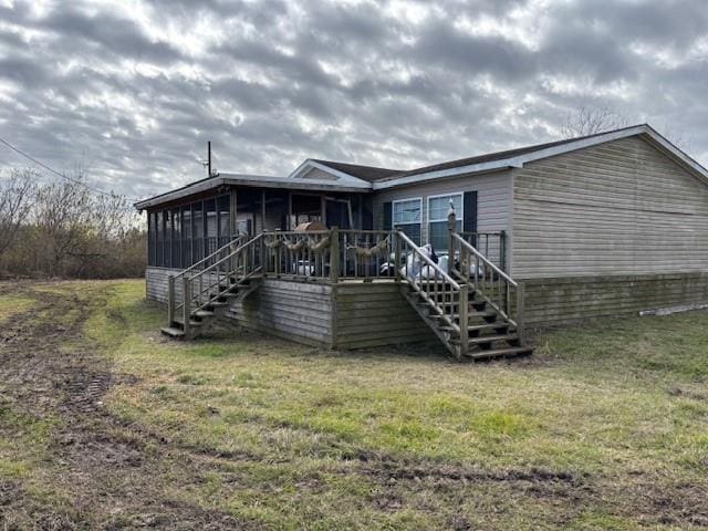 rear view of property featuring a wooden deck, a sunroom, and a lawn