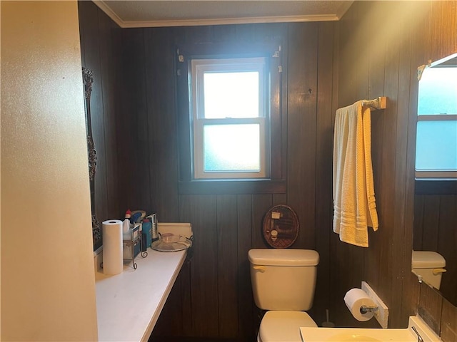 bathroom with toilet, wooden walls, and crown molding