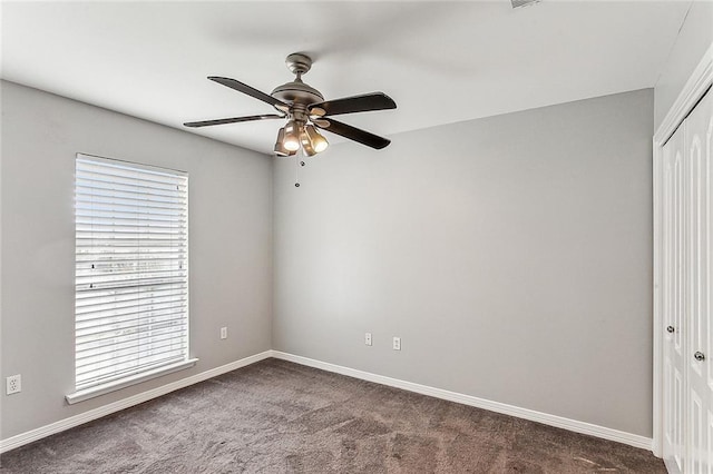 empty room with ceiling fan and dark carpet