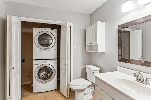 bathroom with stacked washer / drying machine, vanity, toilet, and tile patterned flooring