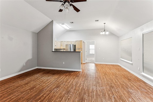 unfurnished living room featuring lofted ceiling, ceiling fan with notable chandelier, and light hardwood / wood-style floors