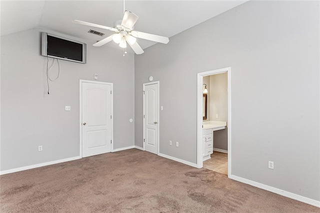 unfurnished bedroom featuring ceiling fan, ensuite bathroom, light colored carpet, and high vaulted ceiling