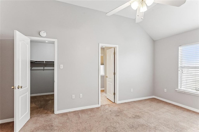 unfurnished bedroom with ceiling fan, light colored carpet, lofted ceiling, multiple windows, and a spacious closet