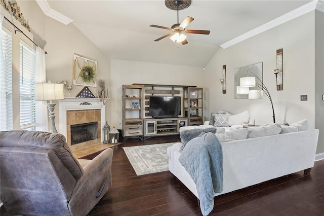 living room featuring ceiling fan, vaulted ceiling, a fireplace, crown molding, and dark wood-type flooring