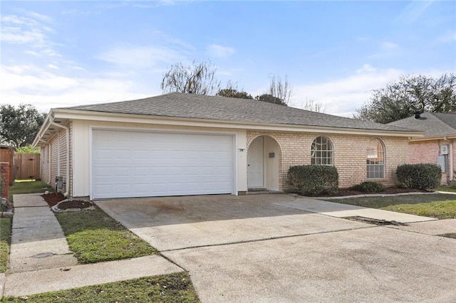 single story home featuring a garage, roof with shingles, concrete driveway, and brick siding