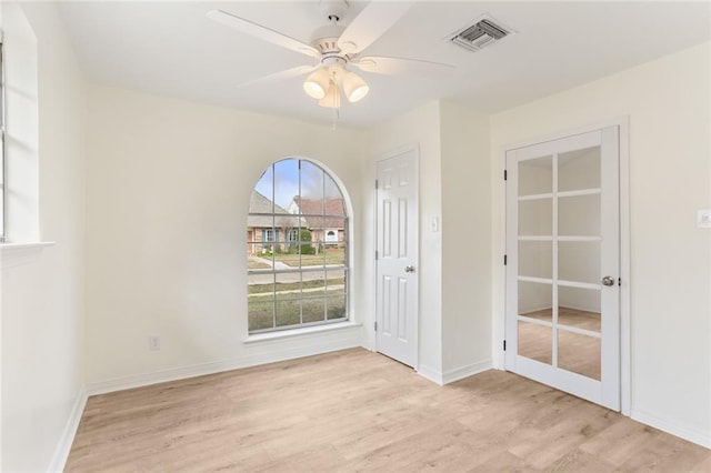 spare room with baseboards, a ceiling fan, visible vents, and light wood-style floors