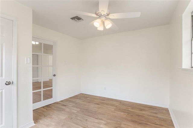 spare room with a ceiling fan, light wood-type flooring, visible vents, and baseboards