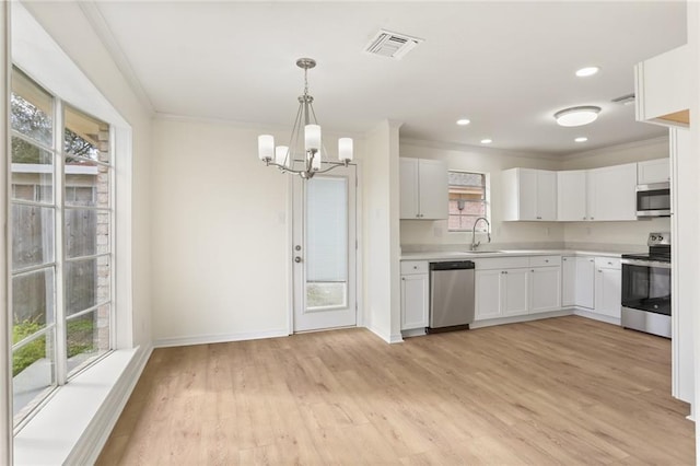 kitchen with stainless steel appliances, light countertops, visible vents, white cabinets, and a sink