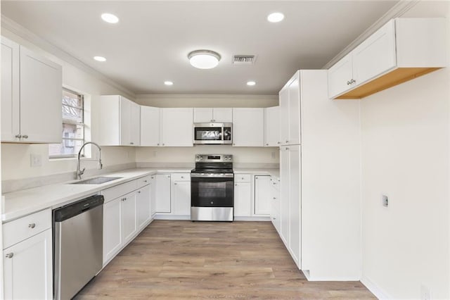 kitchen featuring light countertops, visible vents, appliances with stainless steel finishes, white cabinets, and a sink