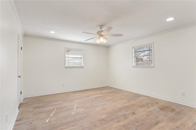 spare room with ornamental molding, light wood-type flooring, a wealth of natural light, and baseboards