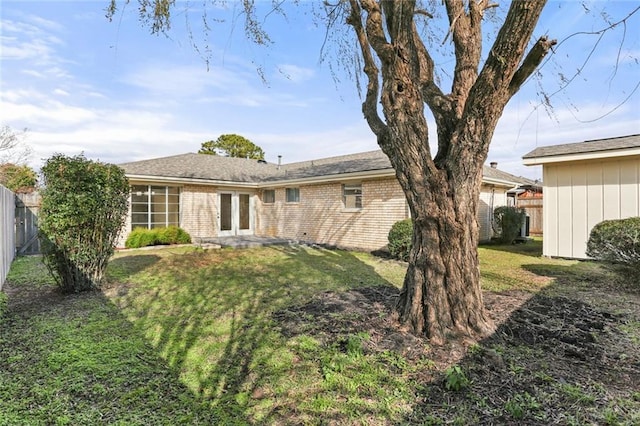 rear view of property featuring a fenced backyard, brick siding, and a lawn