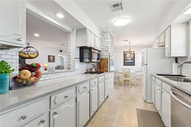 kitchen with white cabinetry, stainless steel appliances, decorative backsplash, sink, and hanging light fixtures