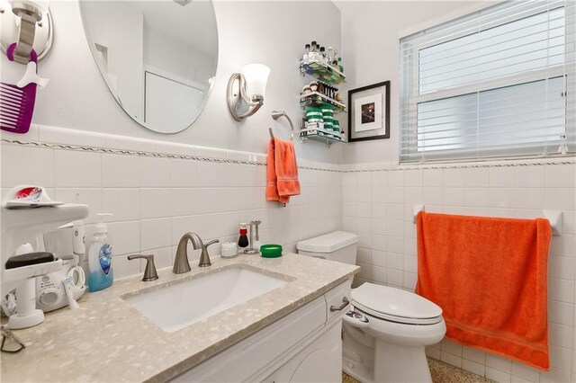 bathroom with toilet, vanity, and tile walls