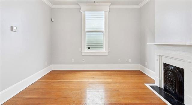 unfurnished living room with crown molding and wood-type flooring