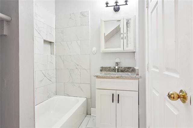 bathroom with tiled shower / bath combo and vanity