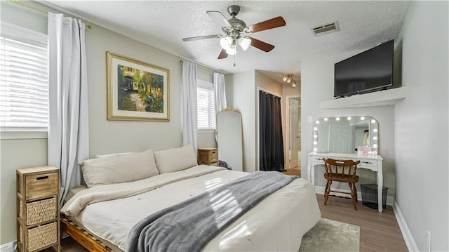 bedroom with light wood-type flooring, ceiling fan, and a textured ceiling