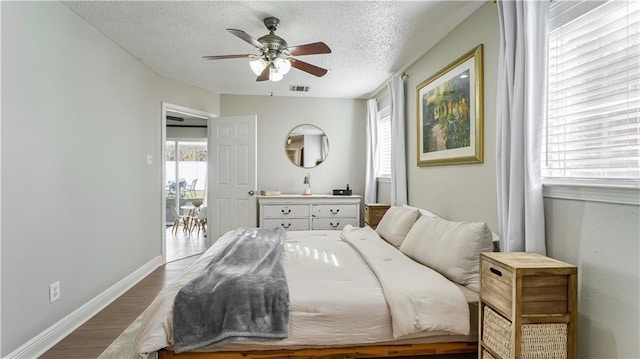 bedroom with ceiling fan, a textured ceiling, and hardwood / wood-style floors