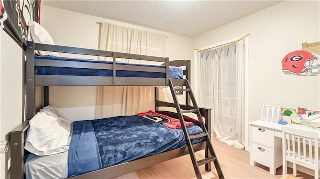 bedroom with a textured ceiling and light hardwood / wood-style flooring