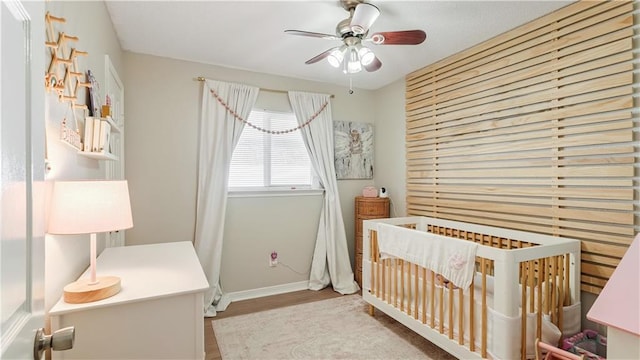 bedroom with ceiling fan and a crib