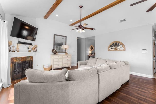 living room featuring a tiled fireplace, dark wood-type flooring, vaulted ceiling with beams, and ceiling fan